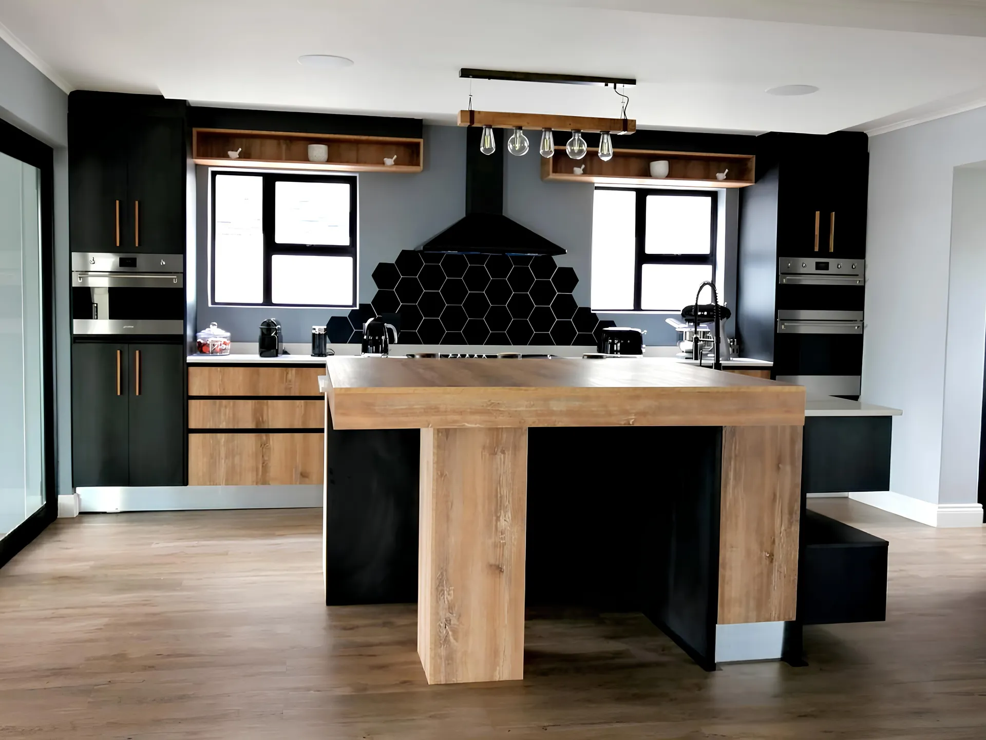Charcoal kitchen cabinetry with an oak waterfall island and hexagon tile splashback, fitted by N.D.I.