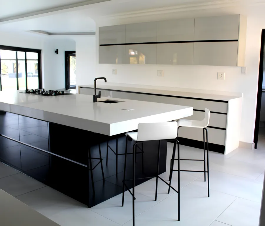 Gloss white kitchen with a black island base and stone waterfall top, fitted by N.D.I.